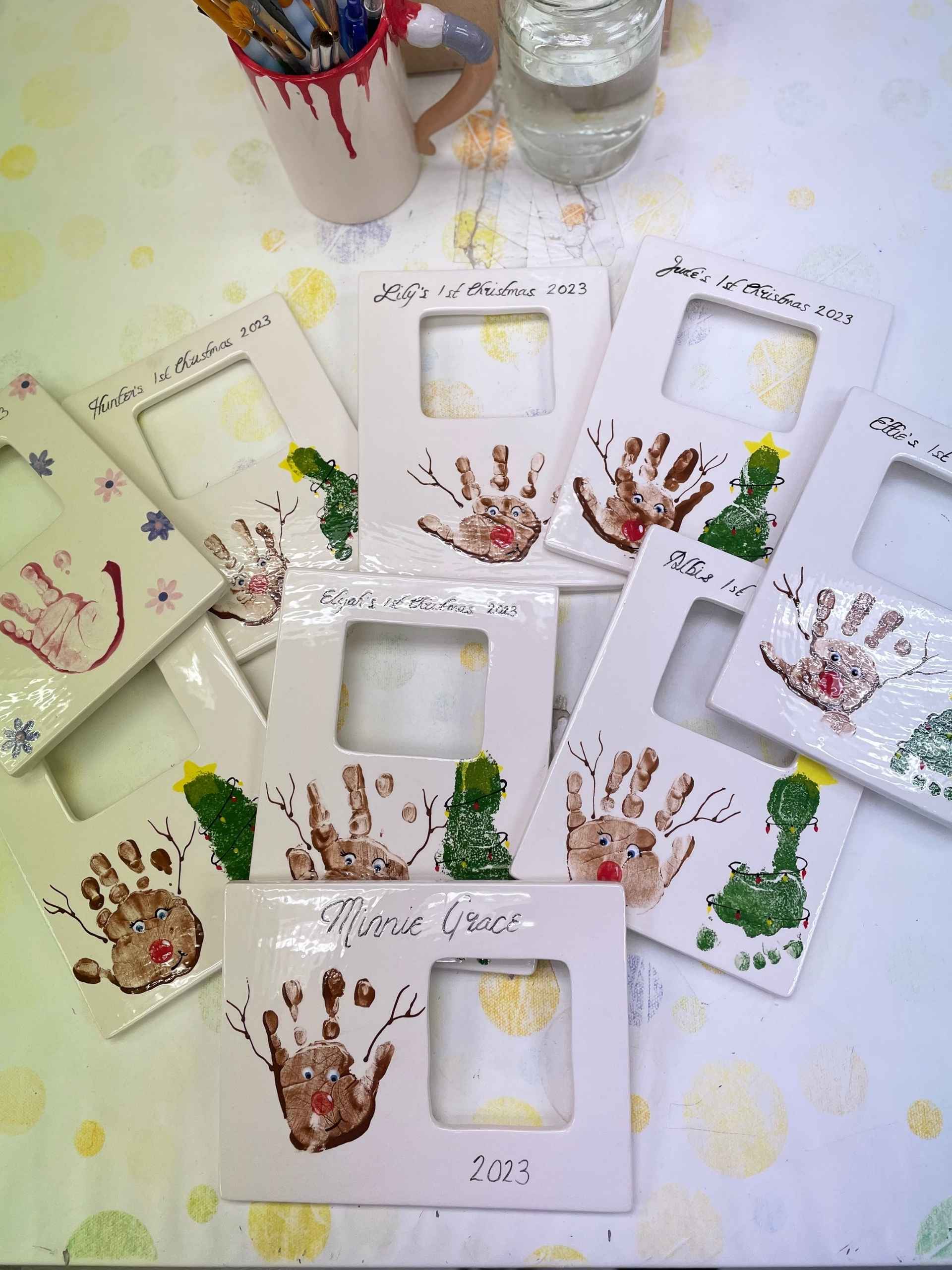 A collection of colourful handprint pieces displayed on a wooden table in a pottery studio, showcasing creativity and artistic expression.