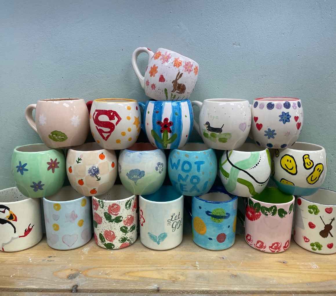 A colourful pile of mugs featuring various unique designs stacked together, showcasing their artistic patterns. The perfect place for crafts in Hillsborough