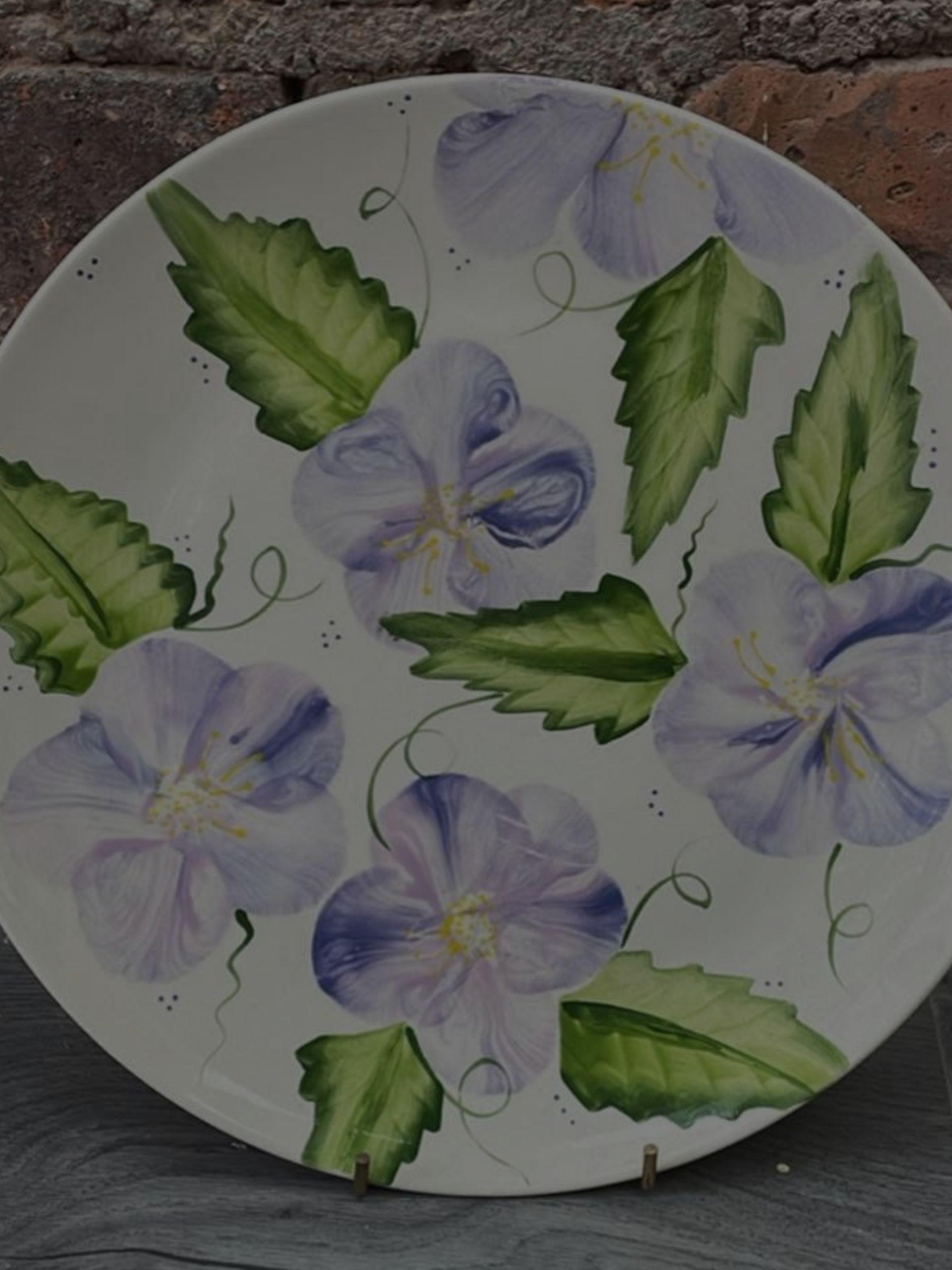 A decorative plate featuring intricate purple flower designs, showcasing vibrant colours and artistic craftsmanship. Pot painting in Hillsborough
