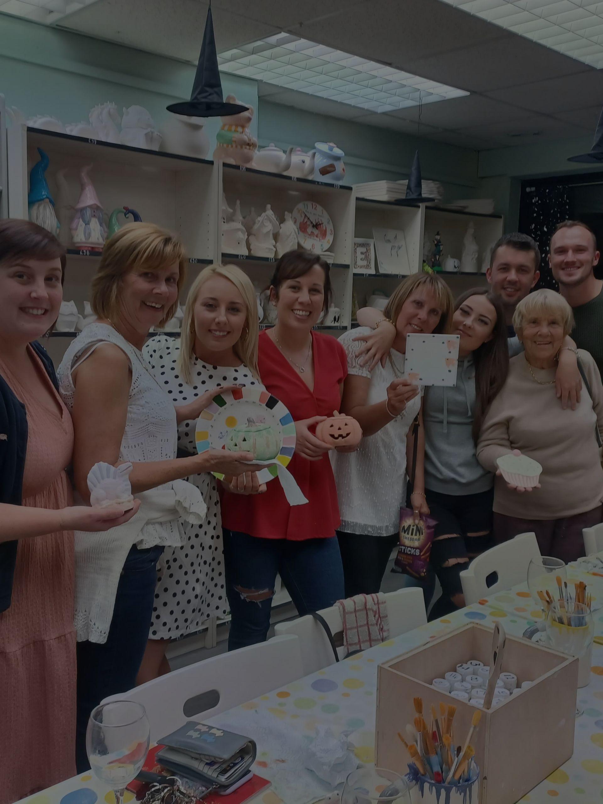Friends gather and pose for a fun photo with their vibrant, creative projects. Pot painting in Hillsborough