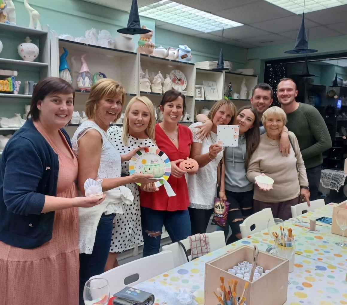 Friends gather and pose for a fun photo with their vibrant, creative projects. The perfect place for crafts in Hillsborough